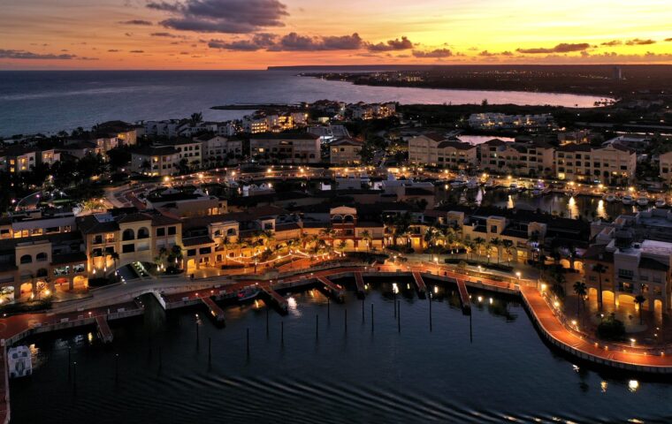 Vista aérea de Ciudad Destino Cap Cana al atardecer, con los edificios residenciales, los muelles y la costa al fondo.